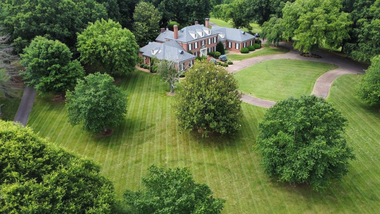Aerial drone view of a large Wilkes County, NC estate lawn with crisp mowing stripes maintained by Quality Lawn & Landscape